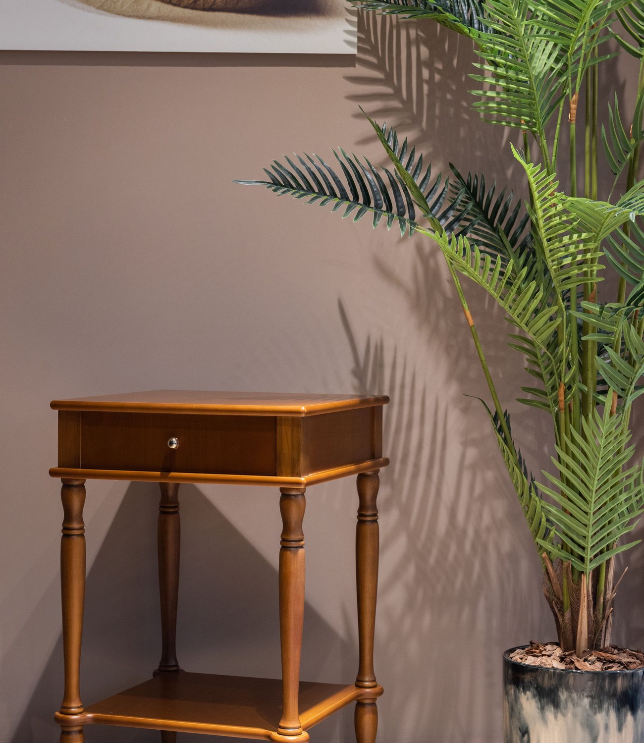 Warm occasional furniture styled beside greenery in a calm neutral room