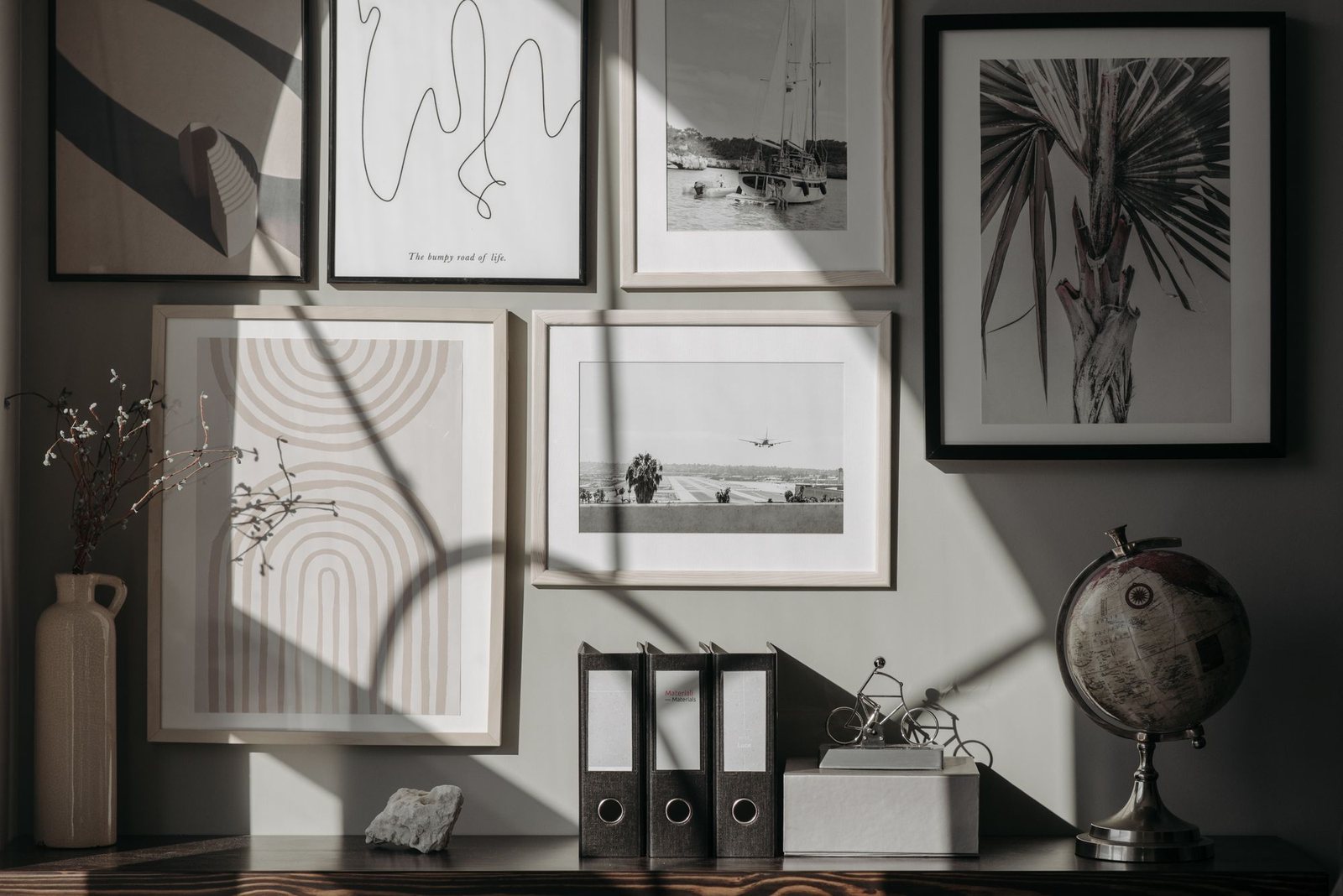 Framed wall art arranged with strong shadows and neutral tone