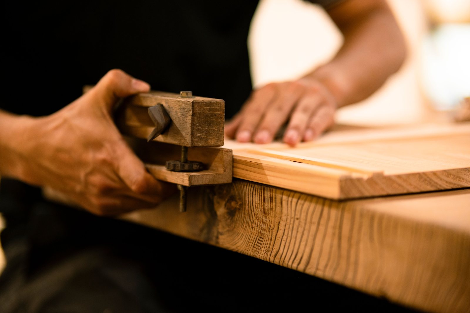 A hand tool shaping warm timber in a workshop